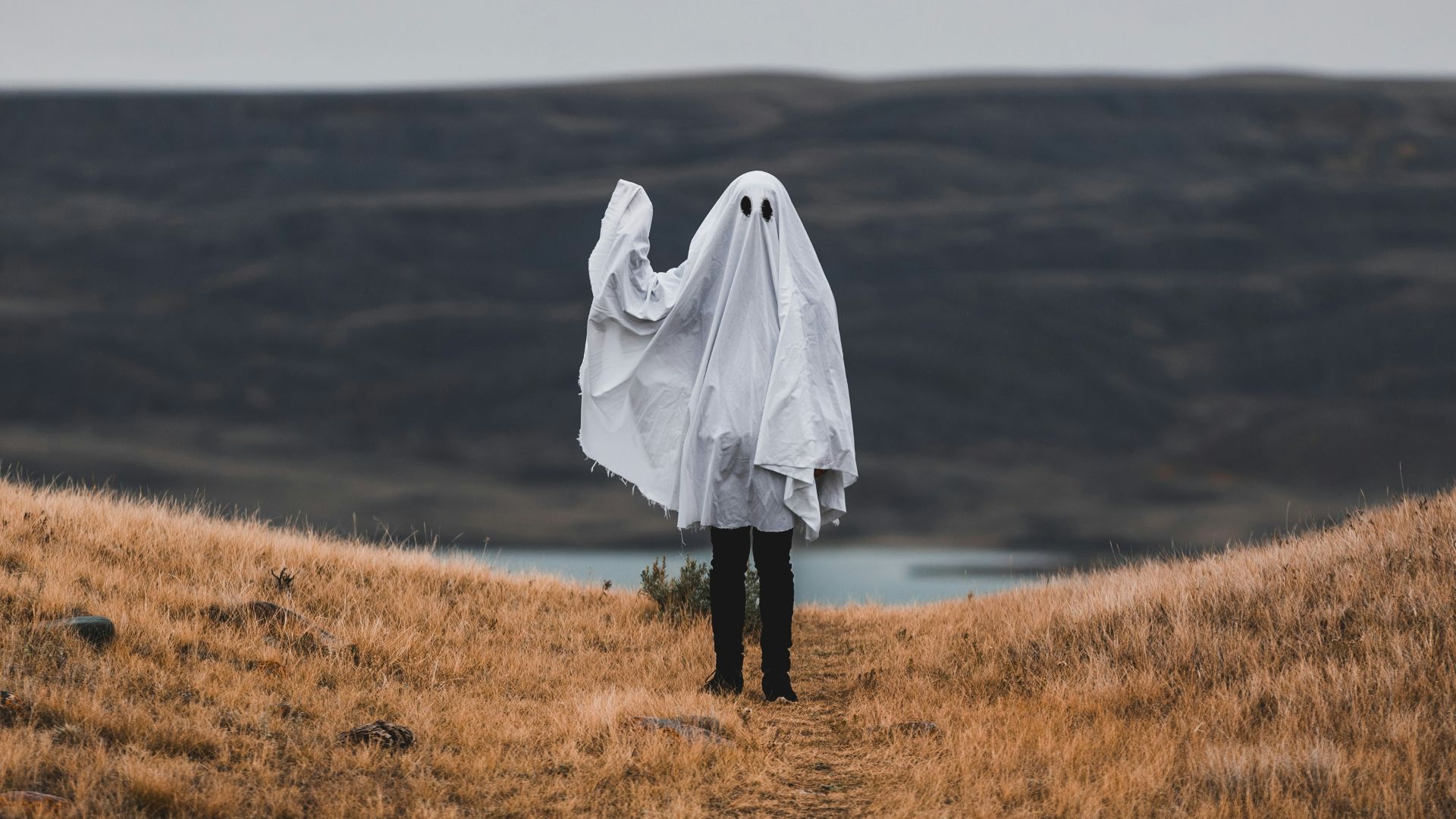 woman in white coat standing on brown grass field during daytime