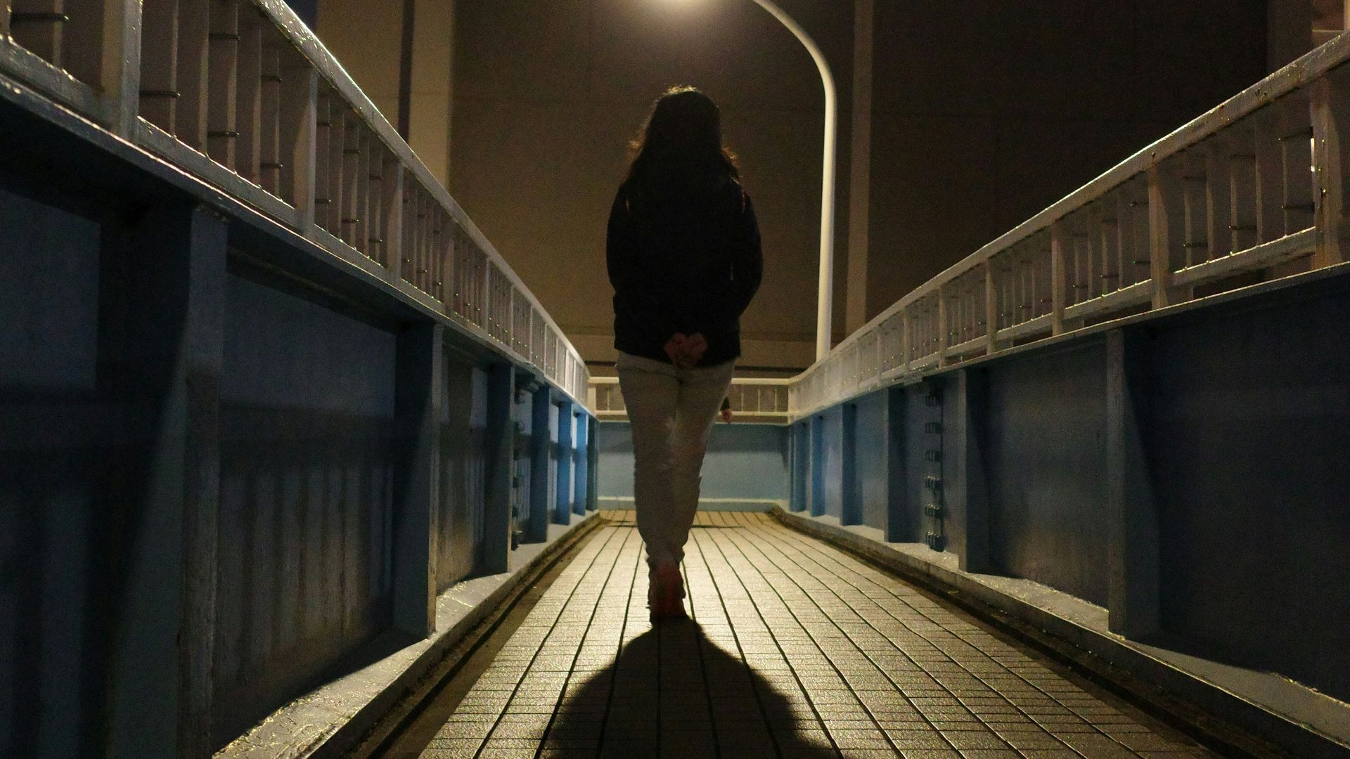a person walking across a bridge at night