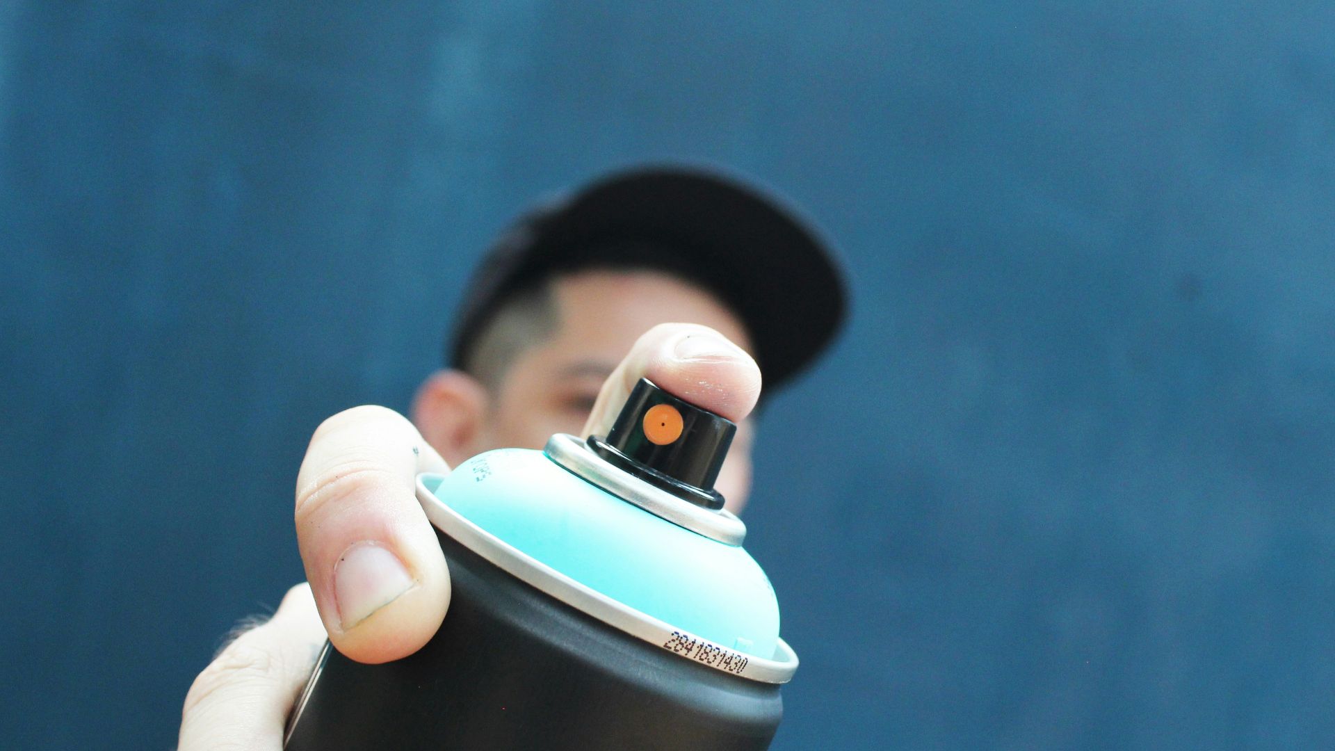 a man holding a black and blue spray can