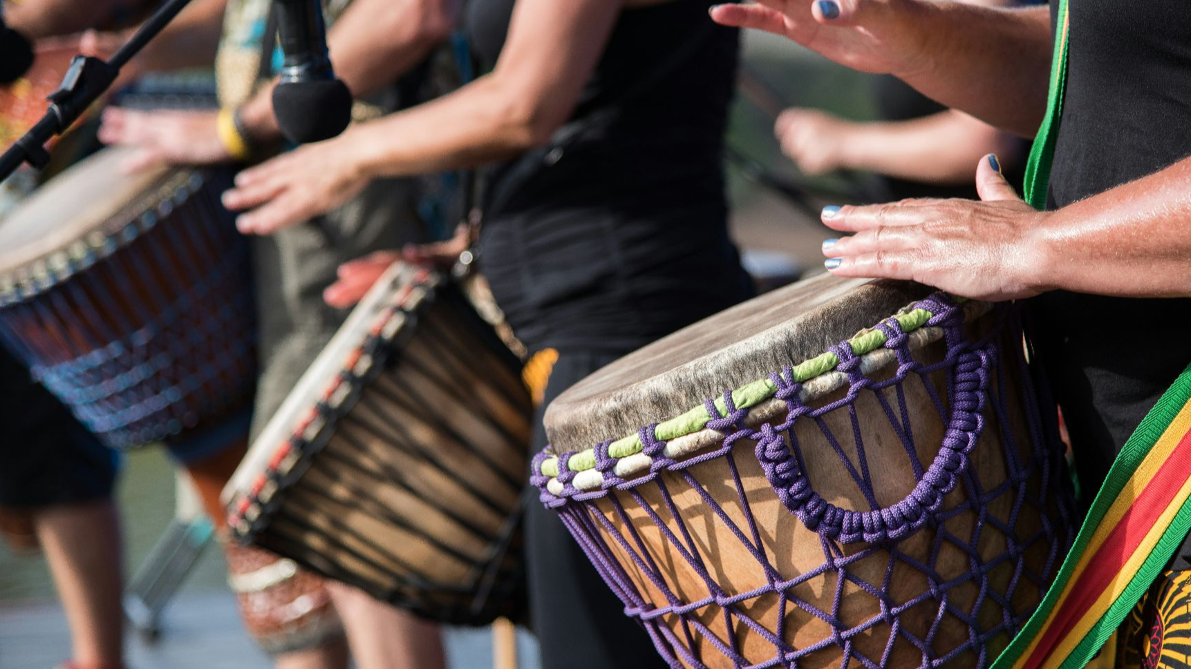 people playing goblet drums during daytime