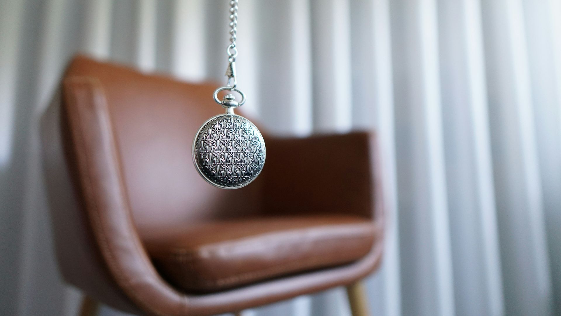 silver round pendant on brown wooden chair