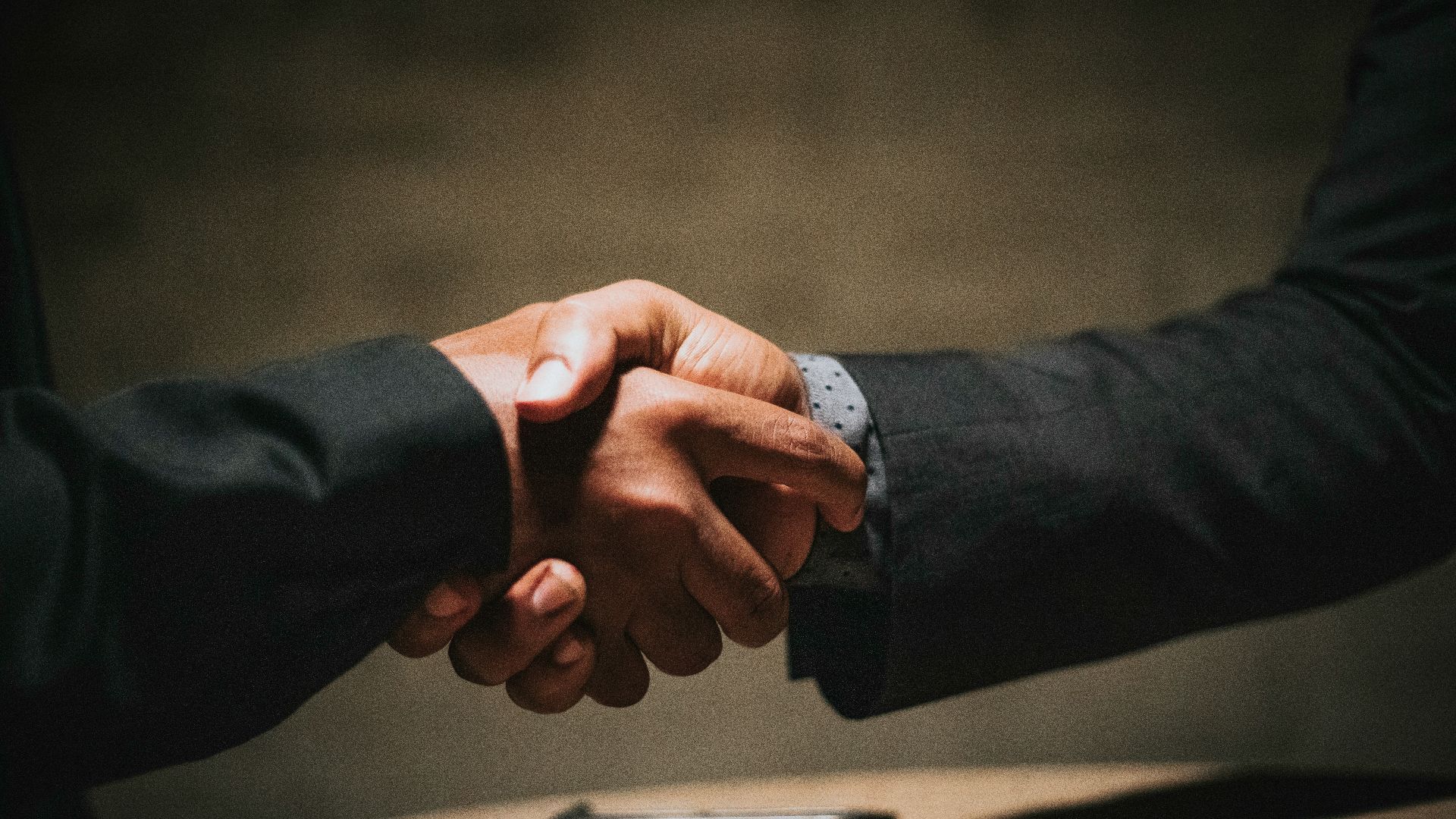two people shaking hands over a wooden table