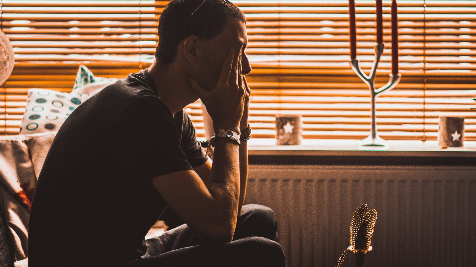 man sitting on chair covering his eyes