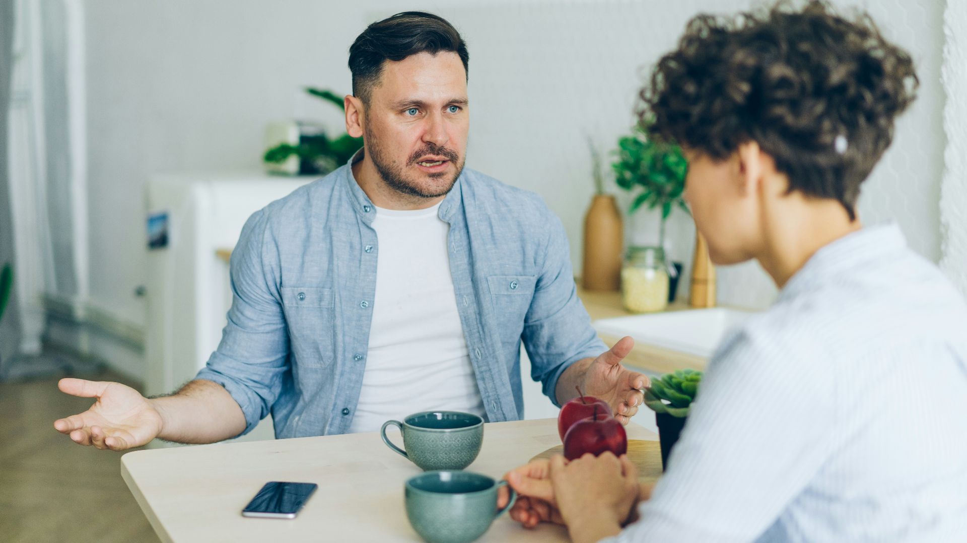 a man sitting at a table talking to a woman