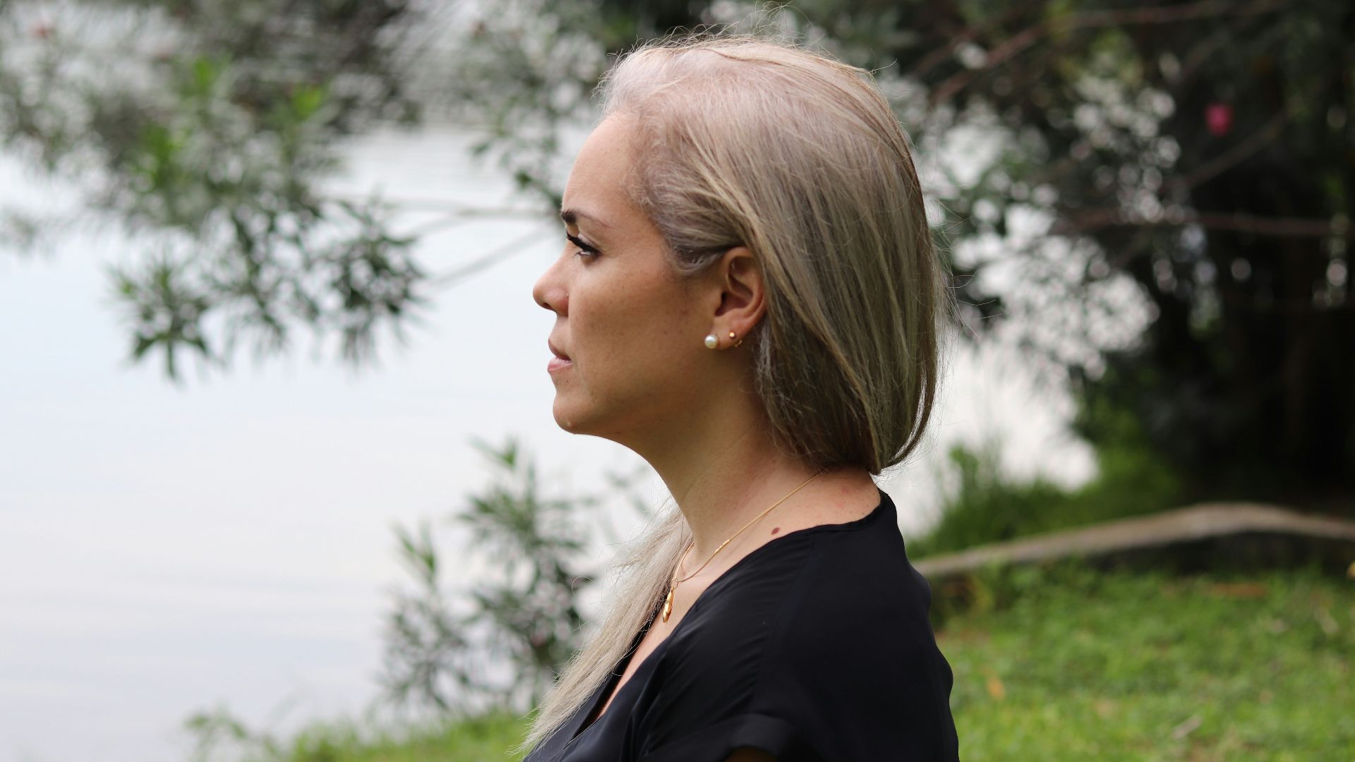 a woman with blonde hair standing in front of a body of water