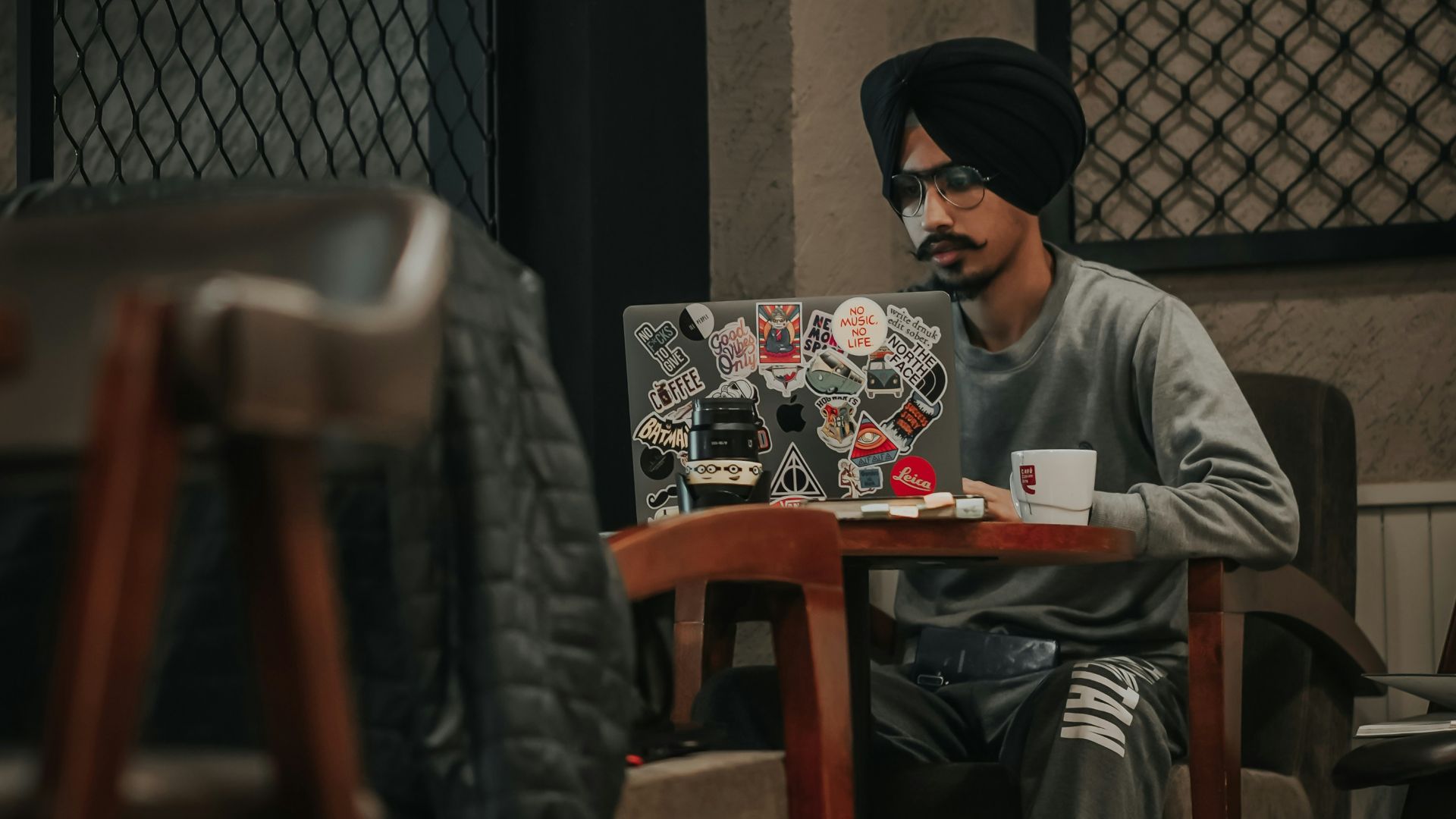 man in gray sweater sitting on brown wooden chair