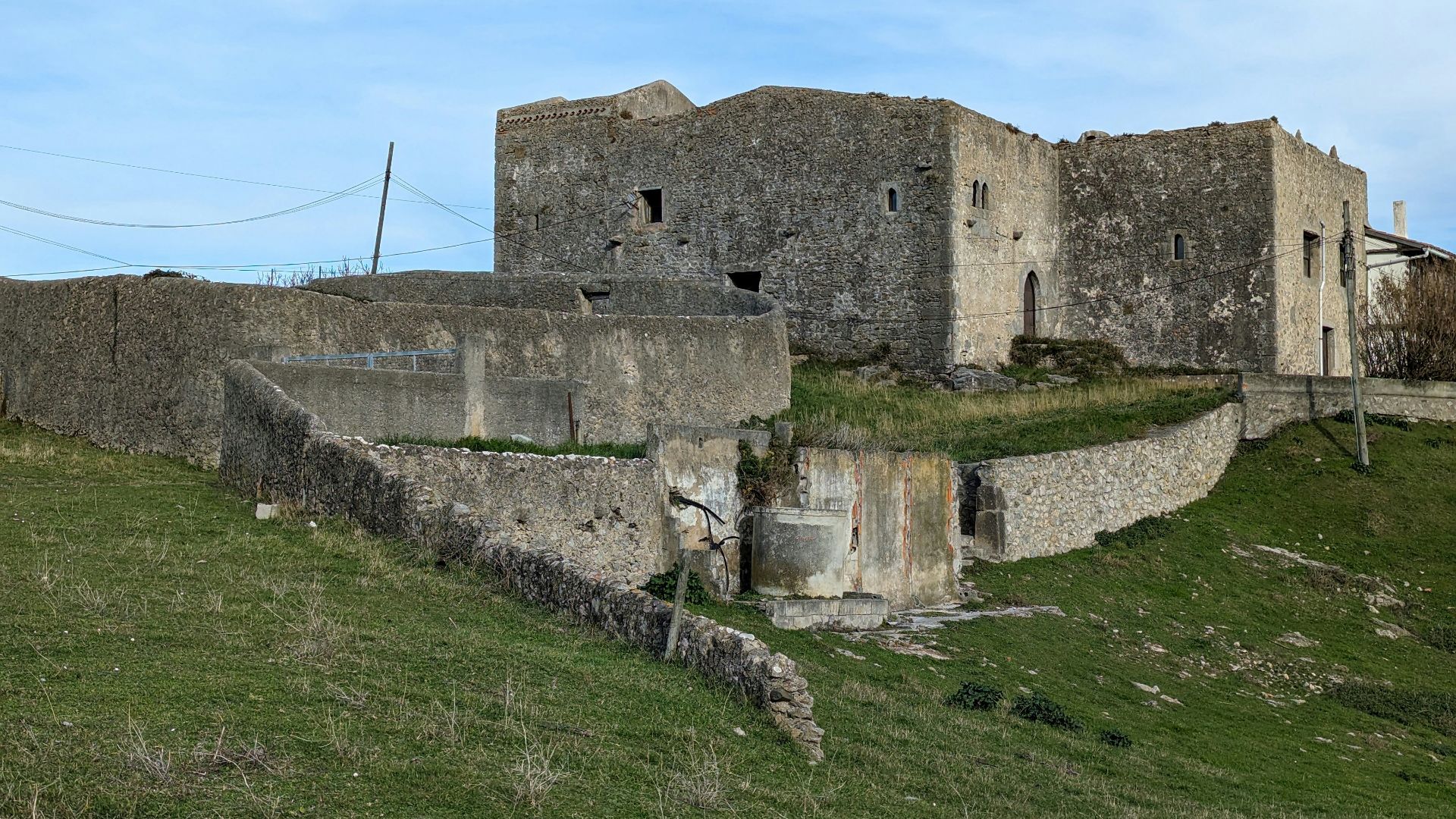 a stone building sitting on top of a lush green hillside