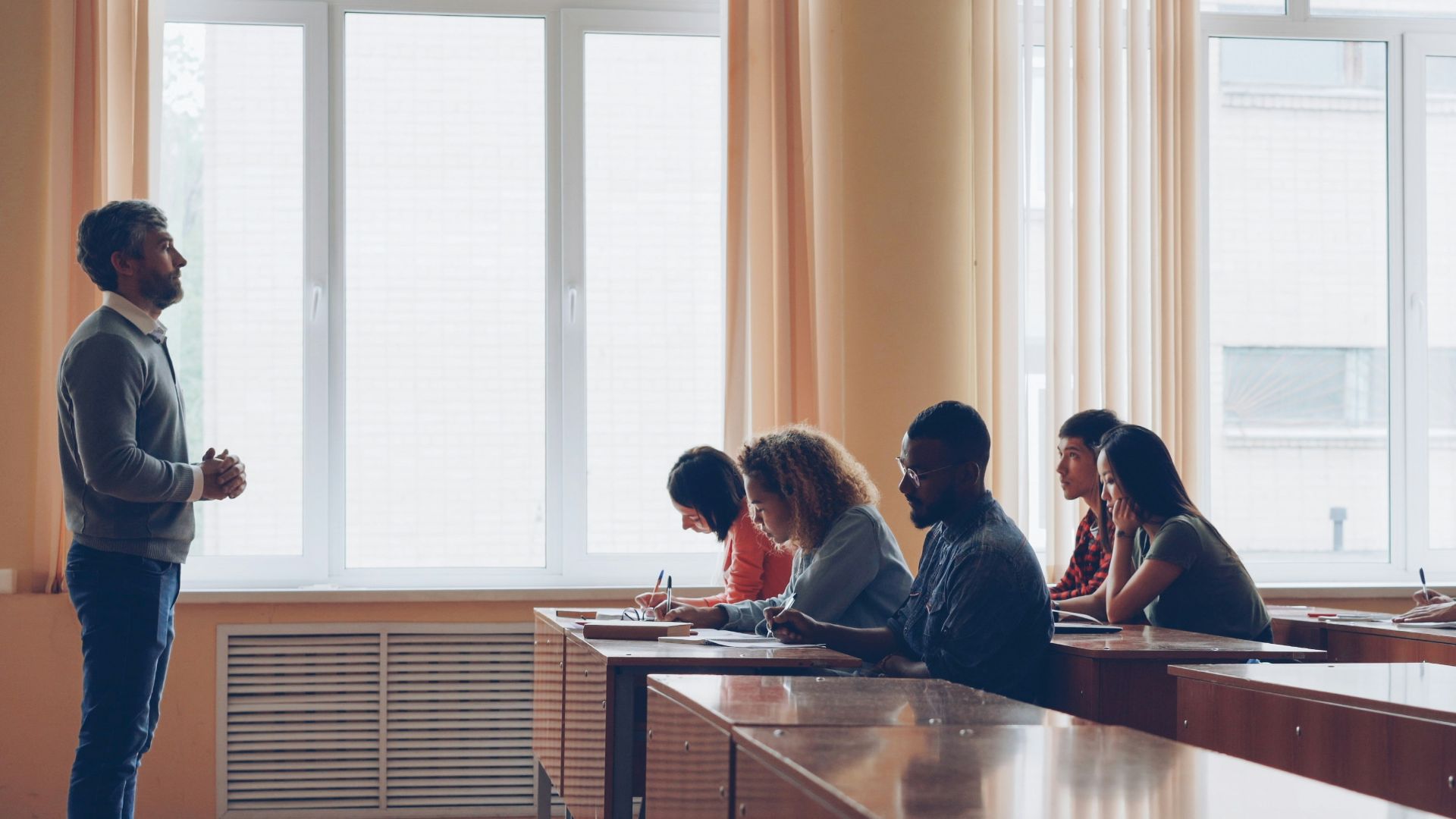 Teacher lecturing students in a classroom setting.