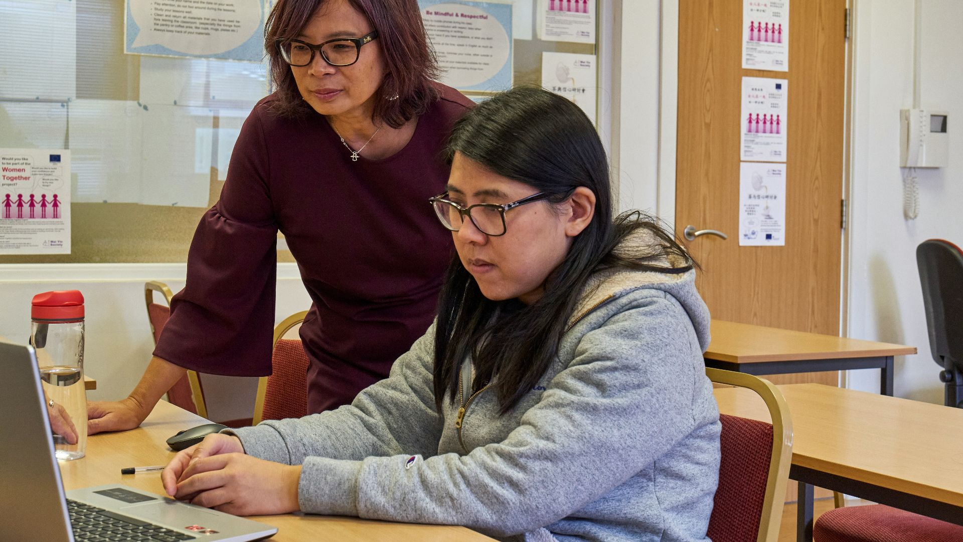 a woman showing a woman something on the laptop