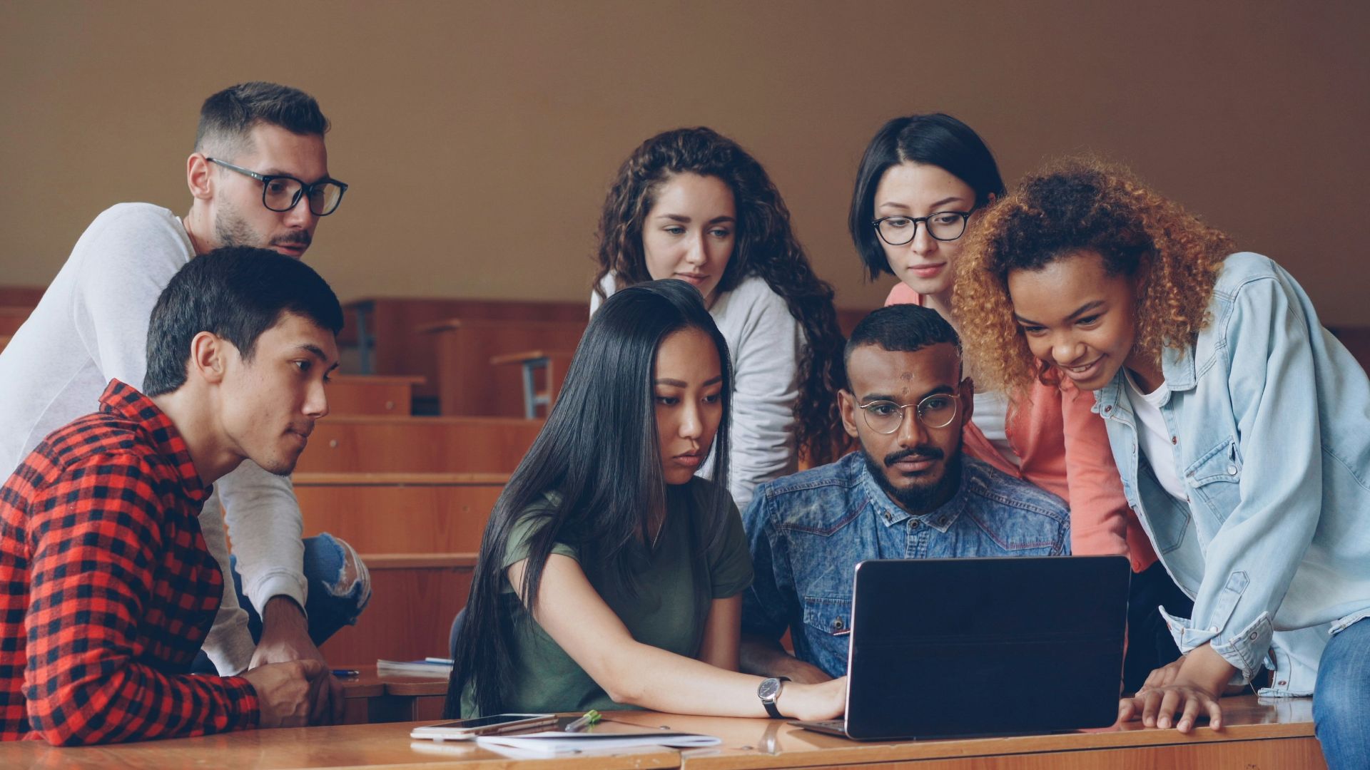 Diverse group of students gathered around laptop