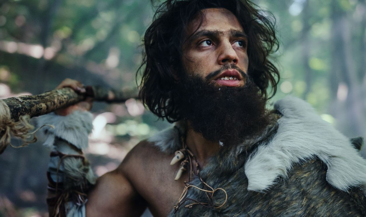 Portrait of Primeval Caveman Wearing Animal Skin and Fur Hunting with a Stone Tipped Spear in the Prehistoric Forest. Prehistoric Neanderthal Screaming, Threatening and Attacking