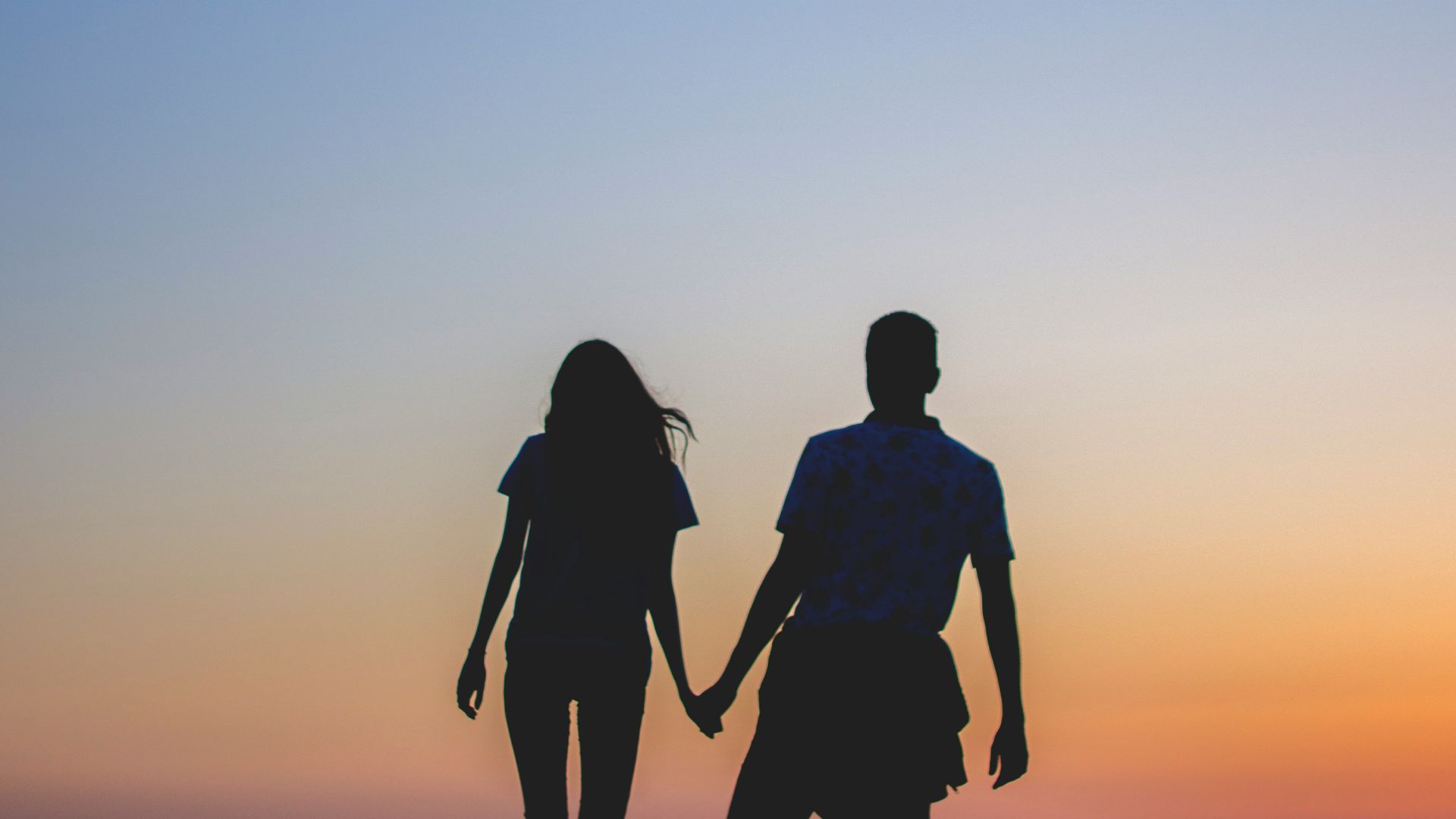 man and woman holding hands in silhouette photography