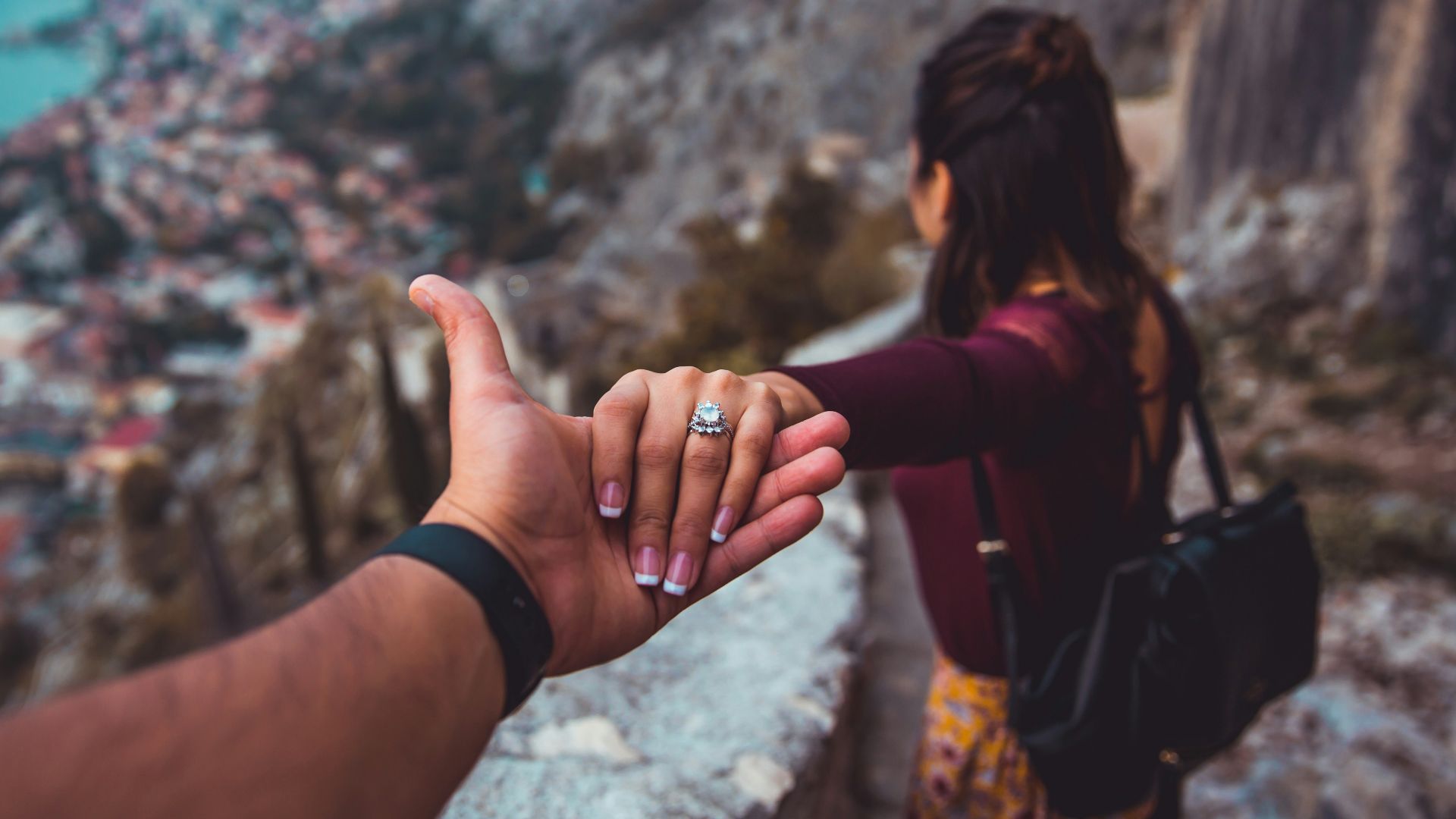 woman holding man's hand while looking on scenery of building beside body of water during daytime