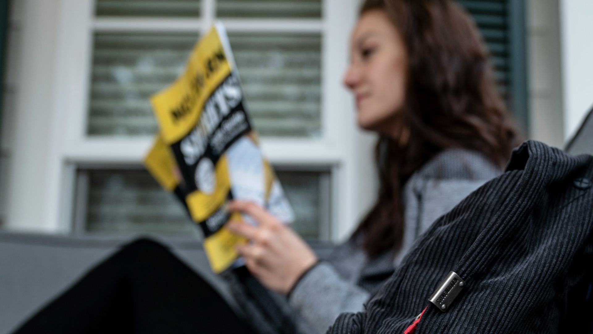 shallow focus photo of black back near woman reading magazine