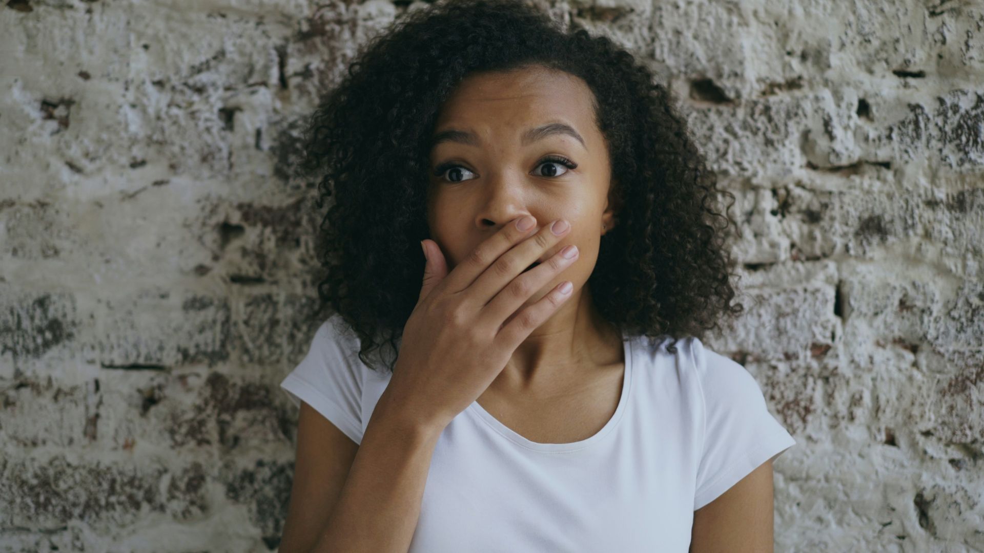 Woman with hand over mouth looking surprised