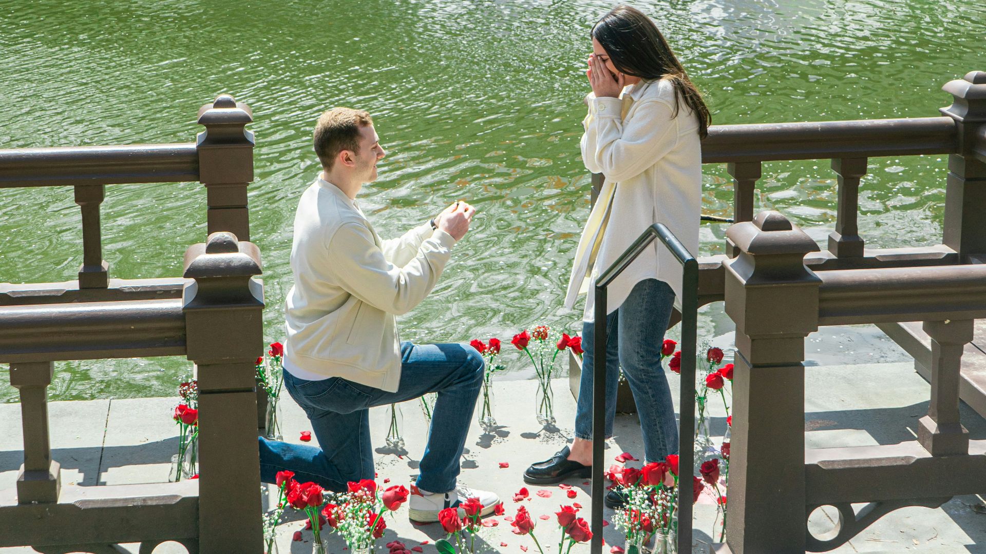 woman in white shirt sitting on brown wooden bench near body of water during daytime