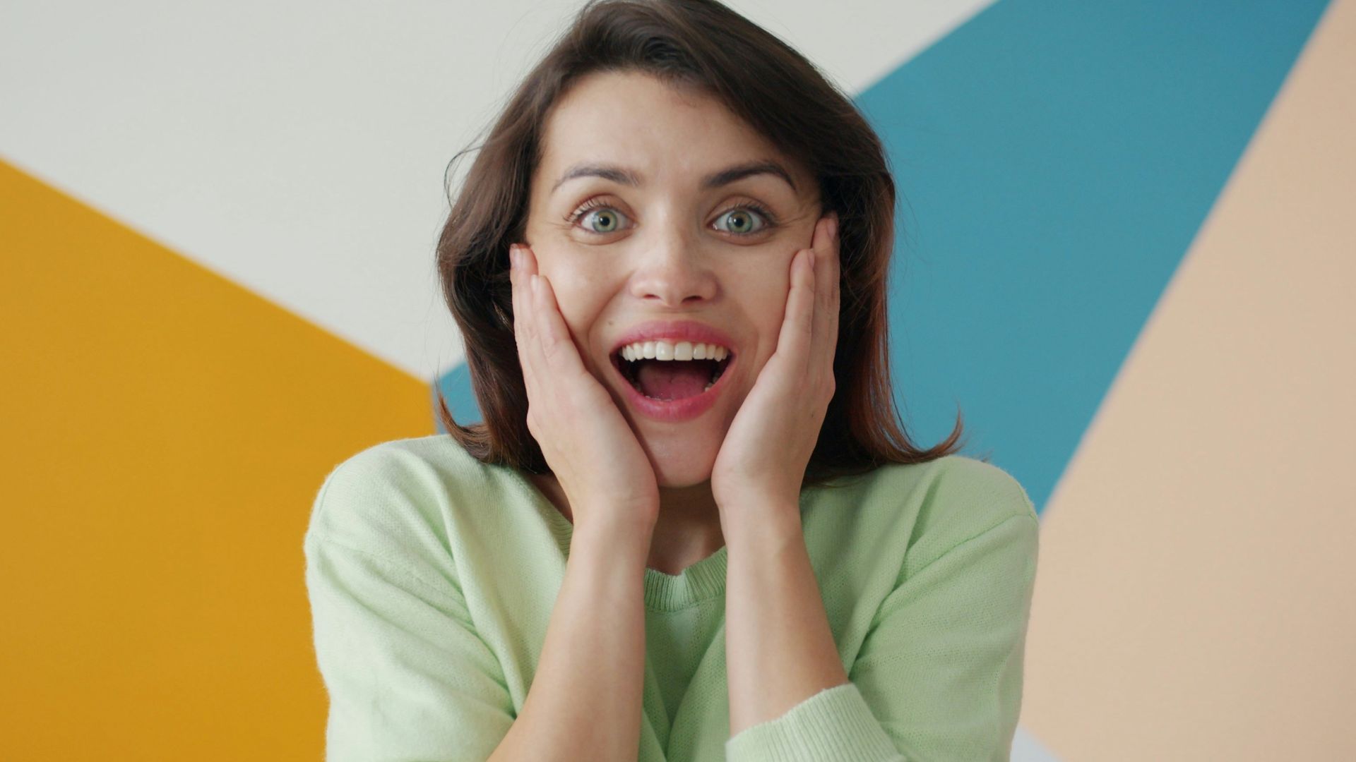 Woman with surprised expression against colorful background