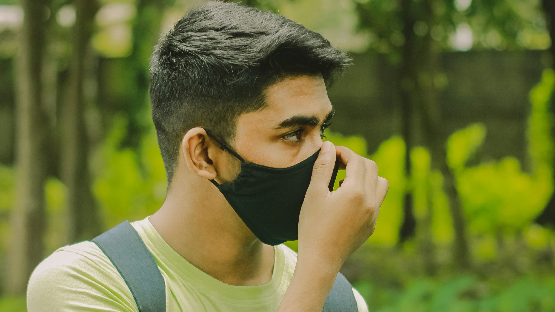 man in white and black tank top covering his face with his hand