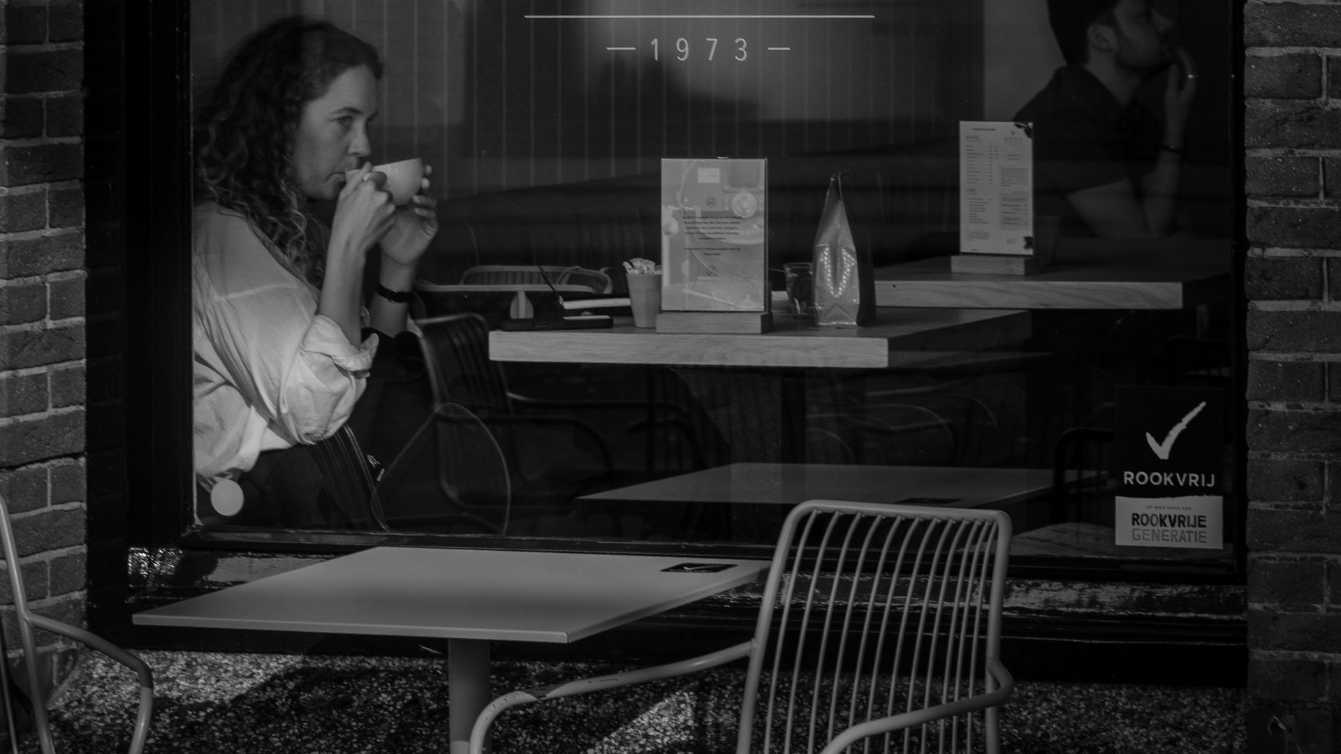 Woman drinking coffee inside a cafe window