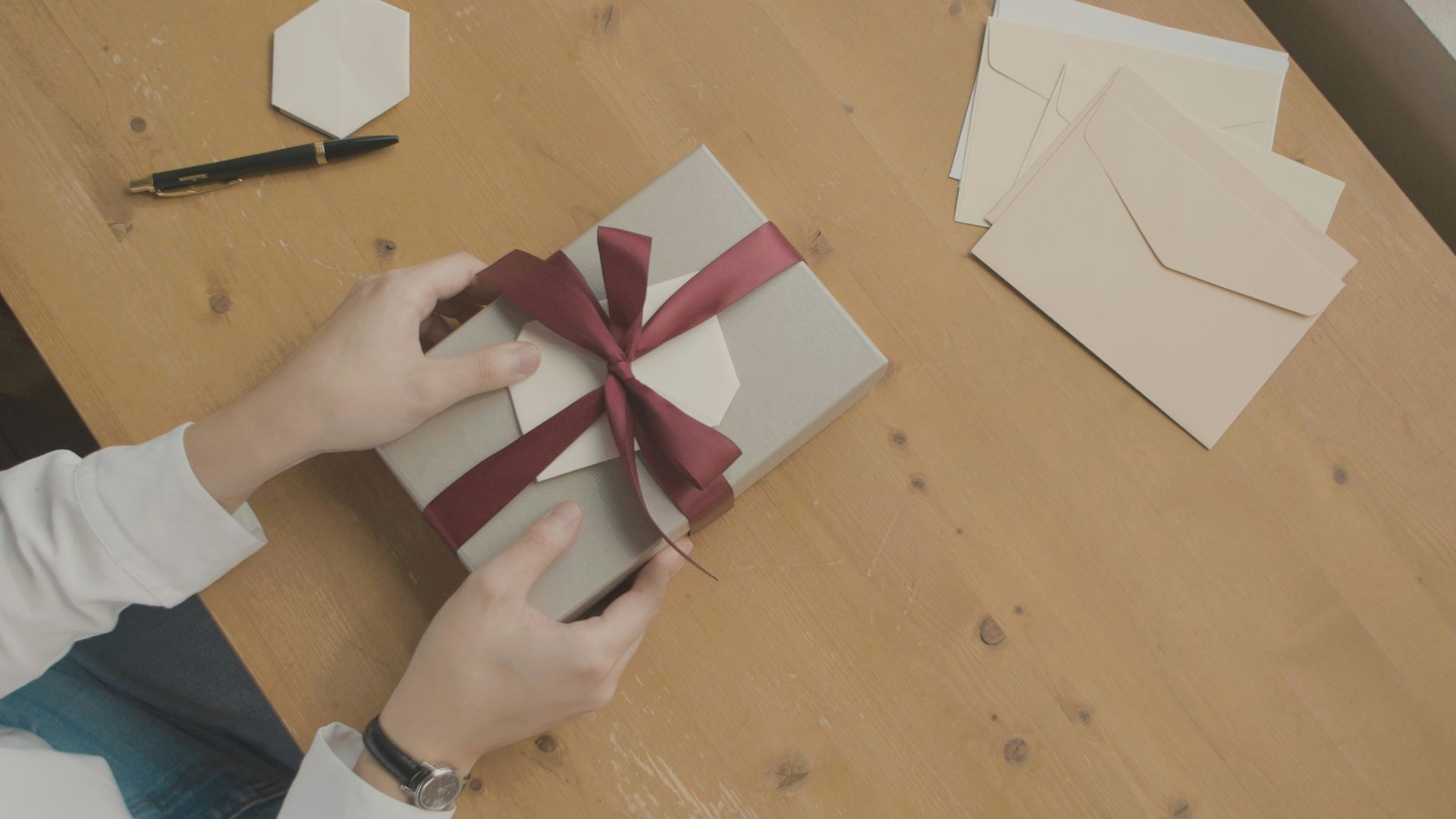 a person opening a gift box with a red ribbon