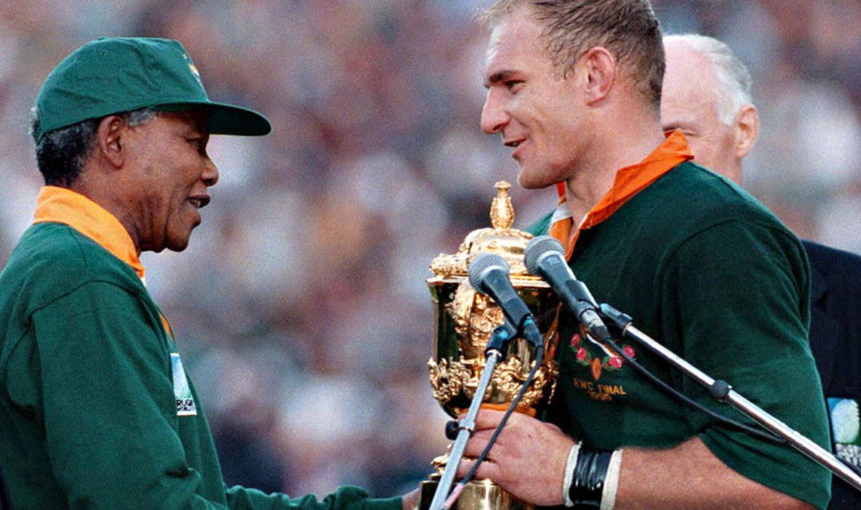 South African president Nelson Mandela, dressed in a No 6 Springbok jersey, congratulates the Springbok captain Francois Pienaar after South Africa beat the All Blacks by 15-12 to win the 1995 Rugby World Cup.