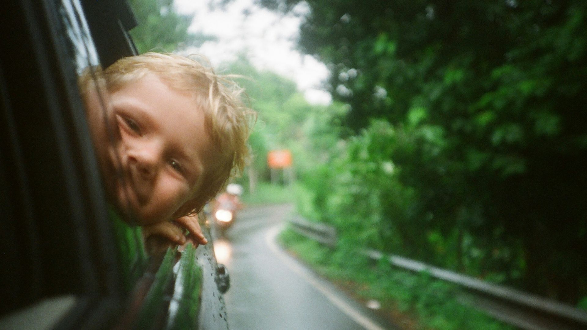 child peeking from vehicle window