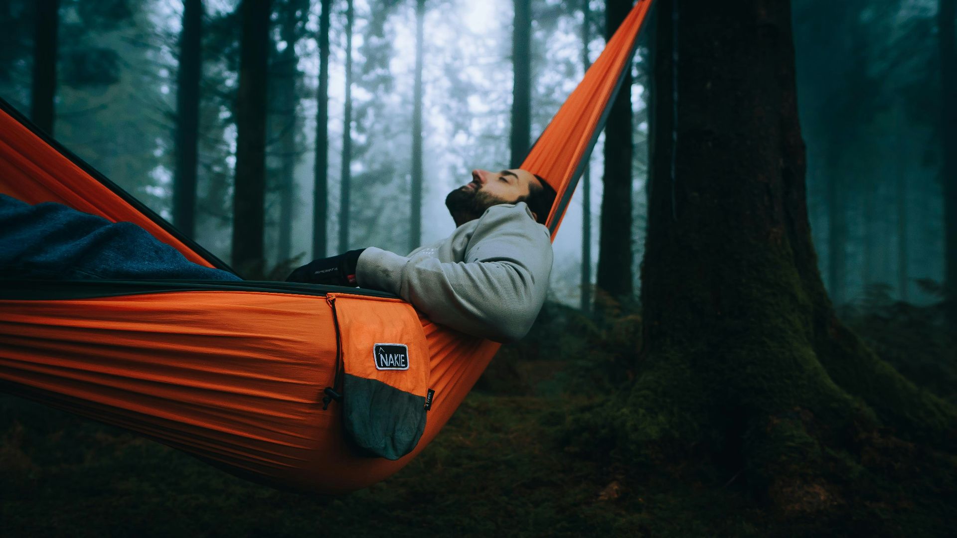 a man laying in a hammock in the woods