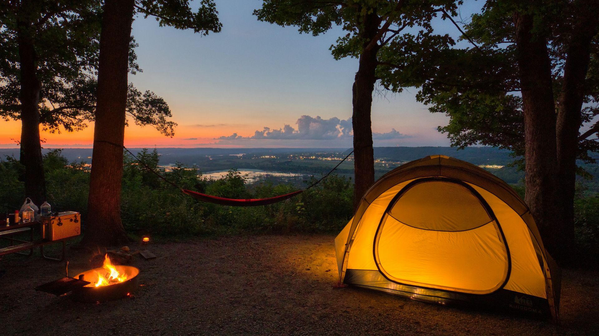 a tent set up in the woods at sunset