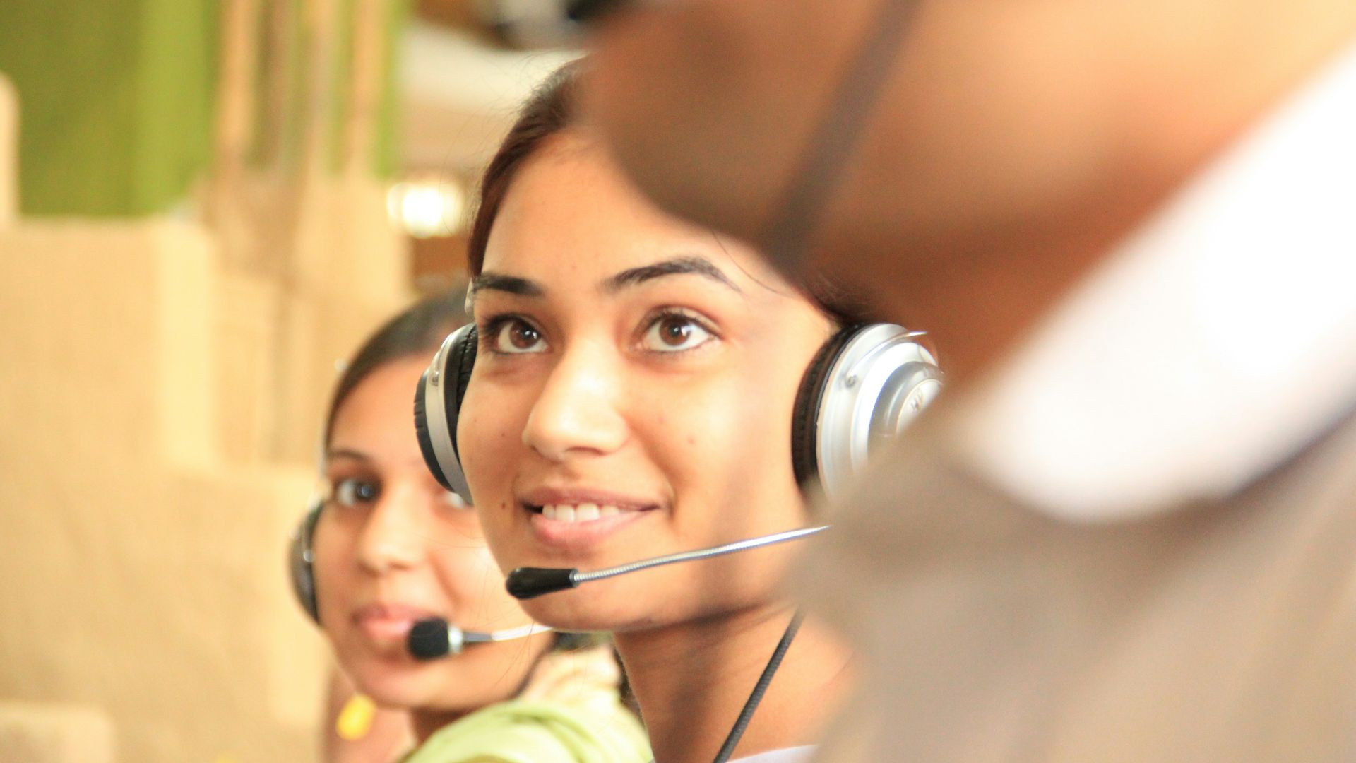 woman in black headphones holding black and silver headphones