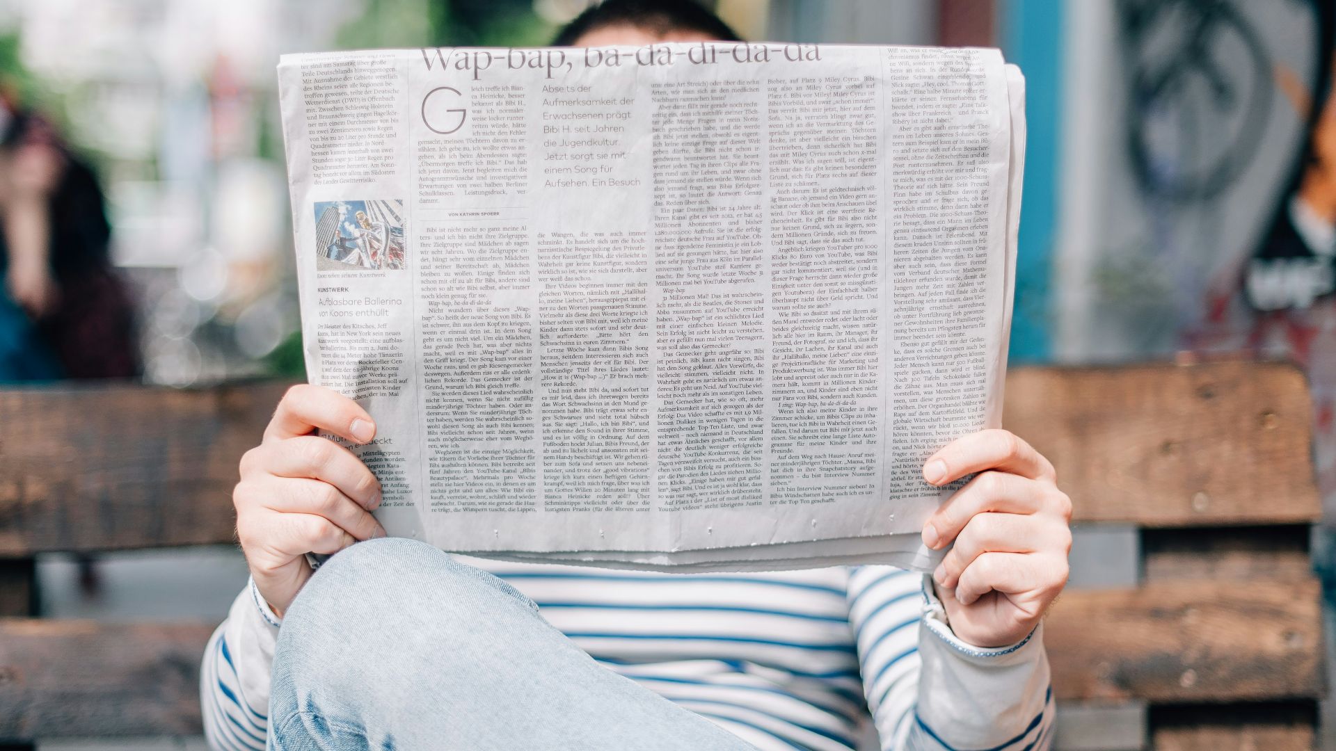 man sitting on bench reading newspaper