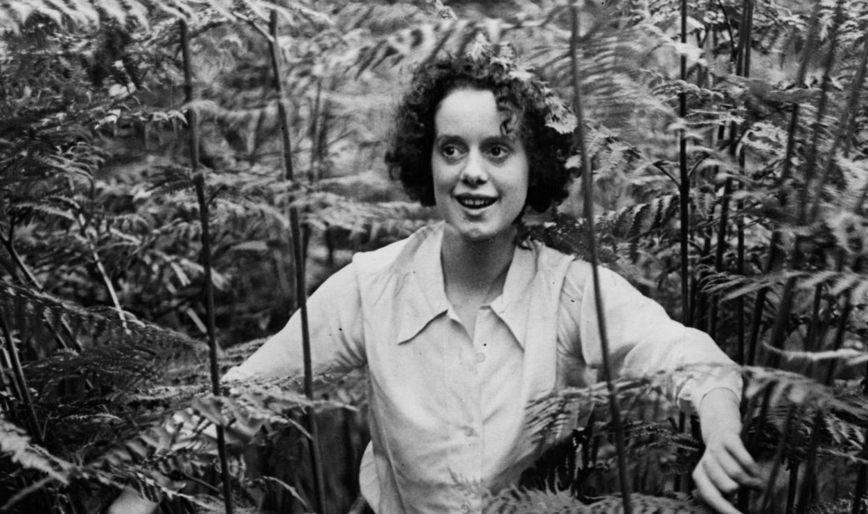 Actress Elsa Lanchester (1902 - 1986) wife of actor Charles Laughton breaking through the bracken in the grounds of 'House in the Treetops' their home in Shere, Surrey.