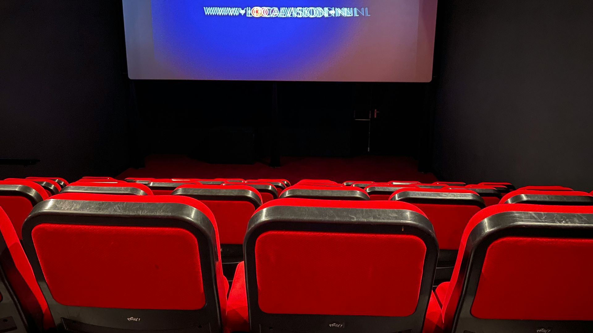 a theater with red seats and a projector screen