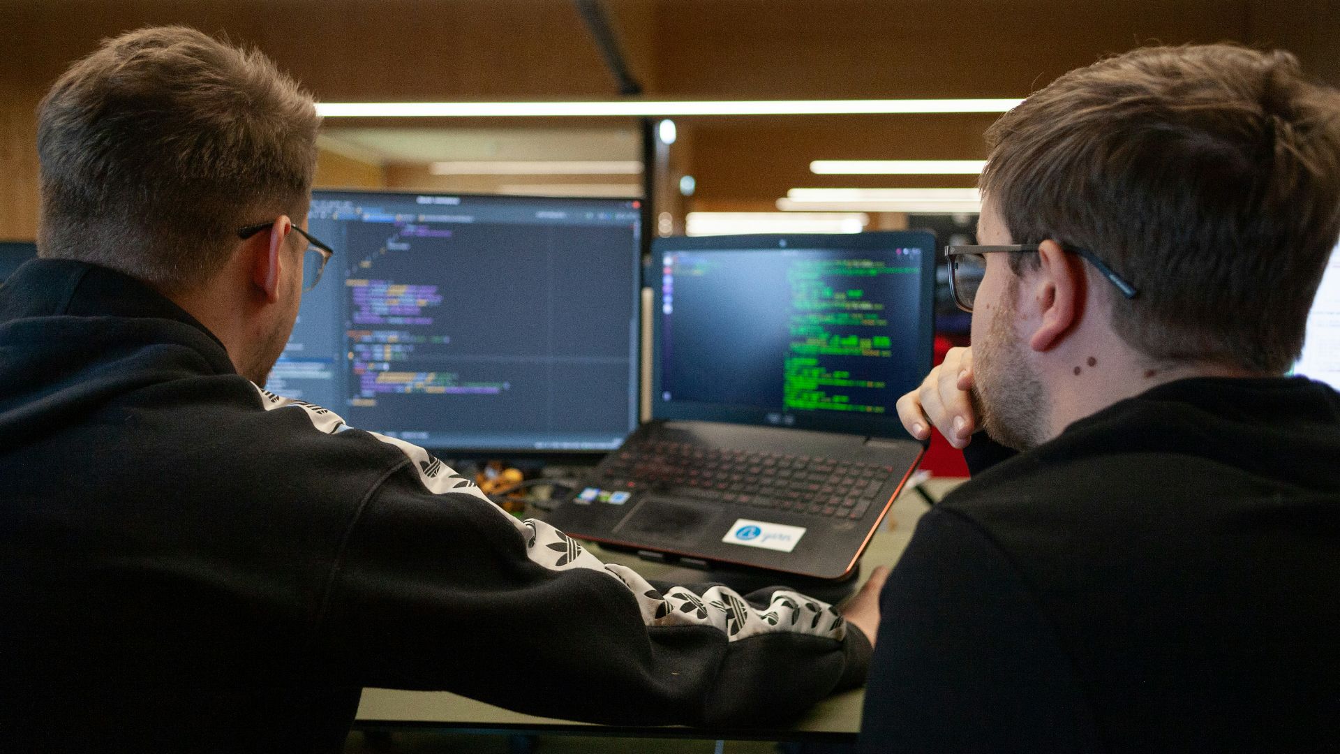two men sitting in front of a laptop computer