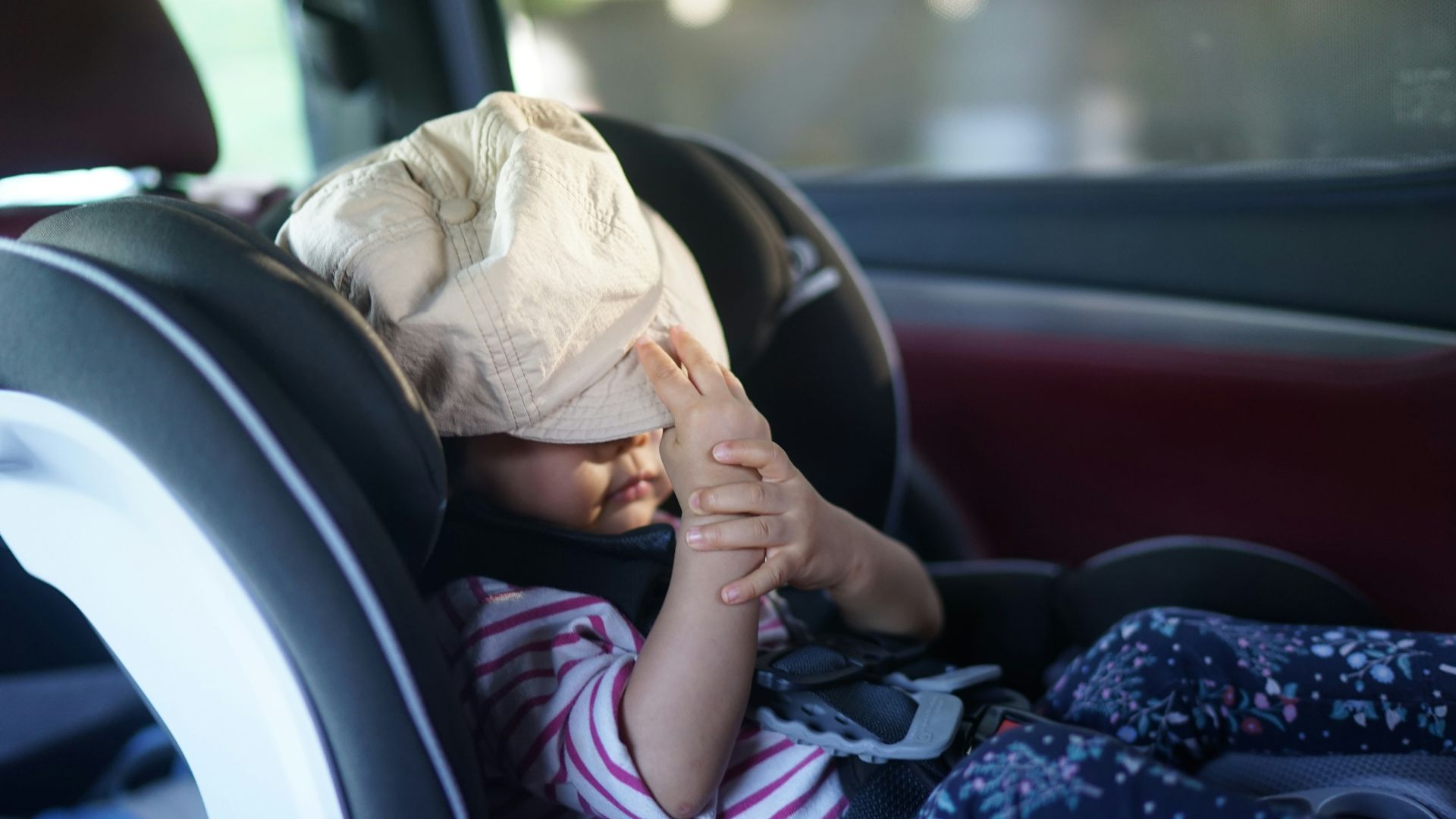 A child has a bag over their head in car.