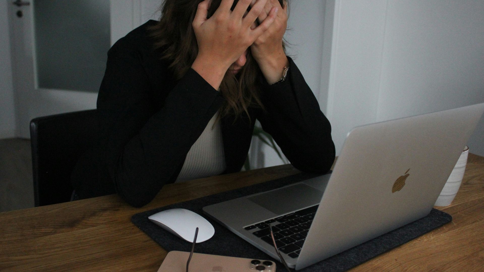 a woman covering her face while looking at a laptop