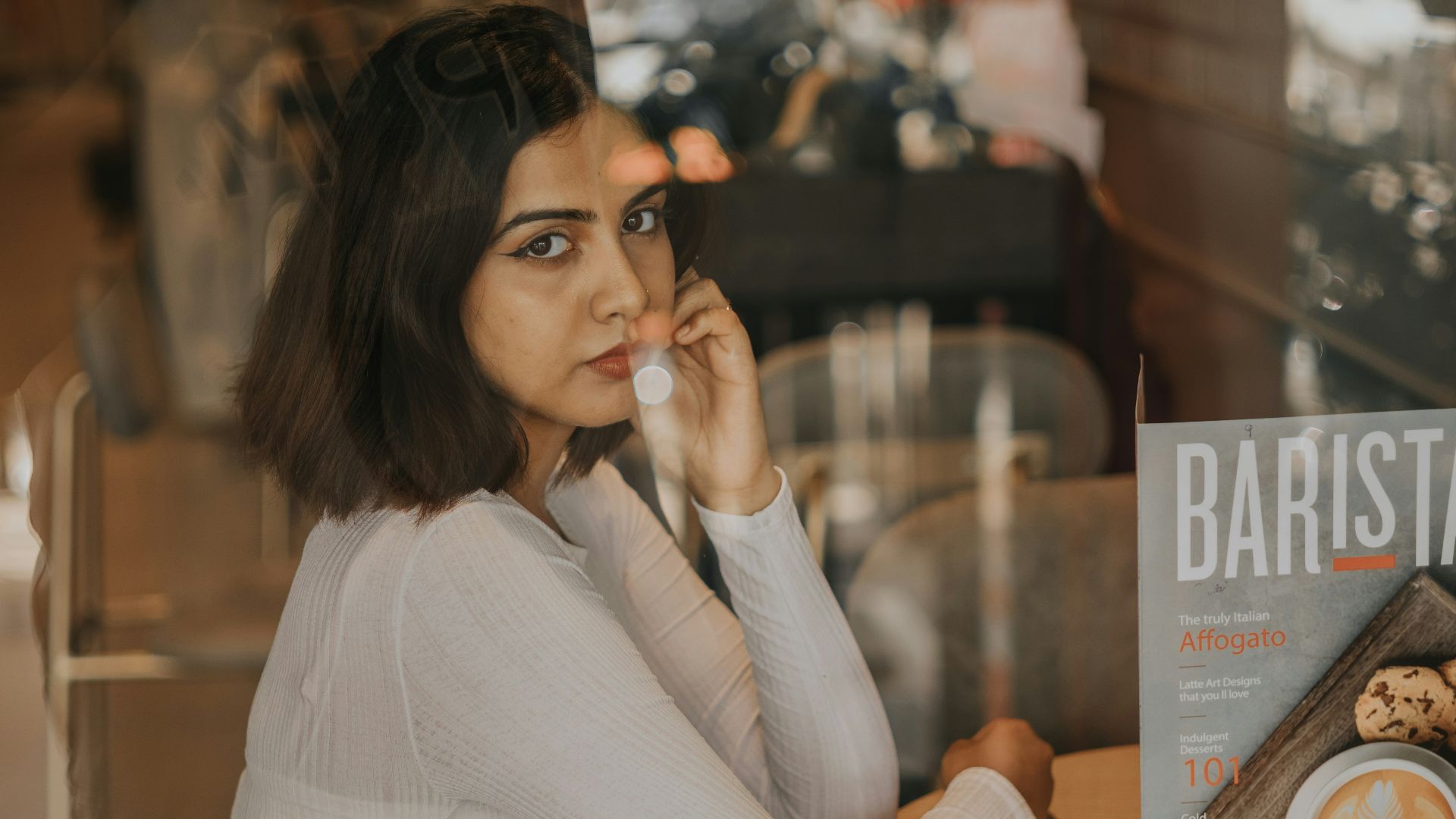 a woman sitting at a table talking on a cell phone