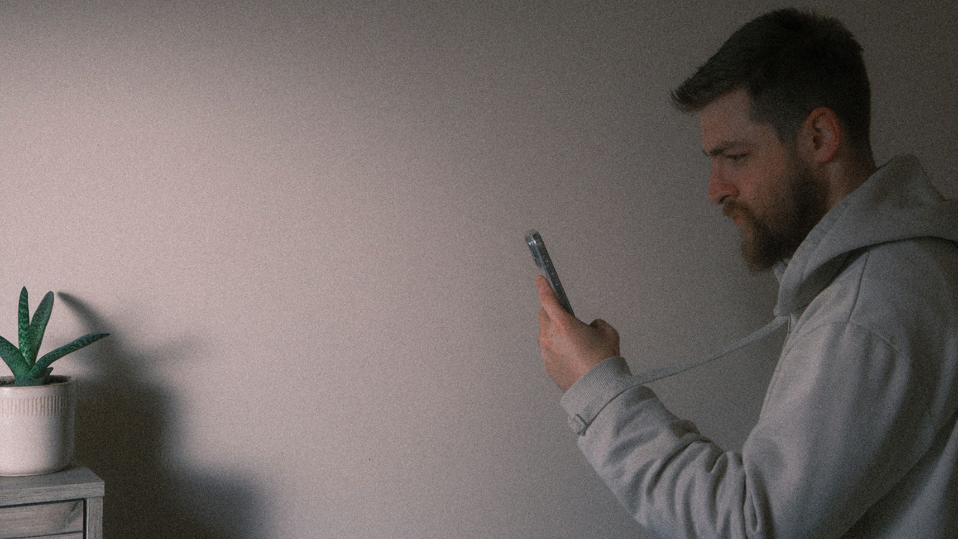 a man holding a cell phone next to a plant