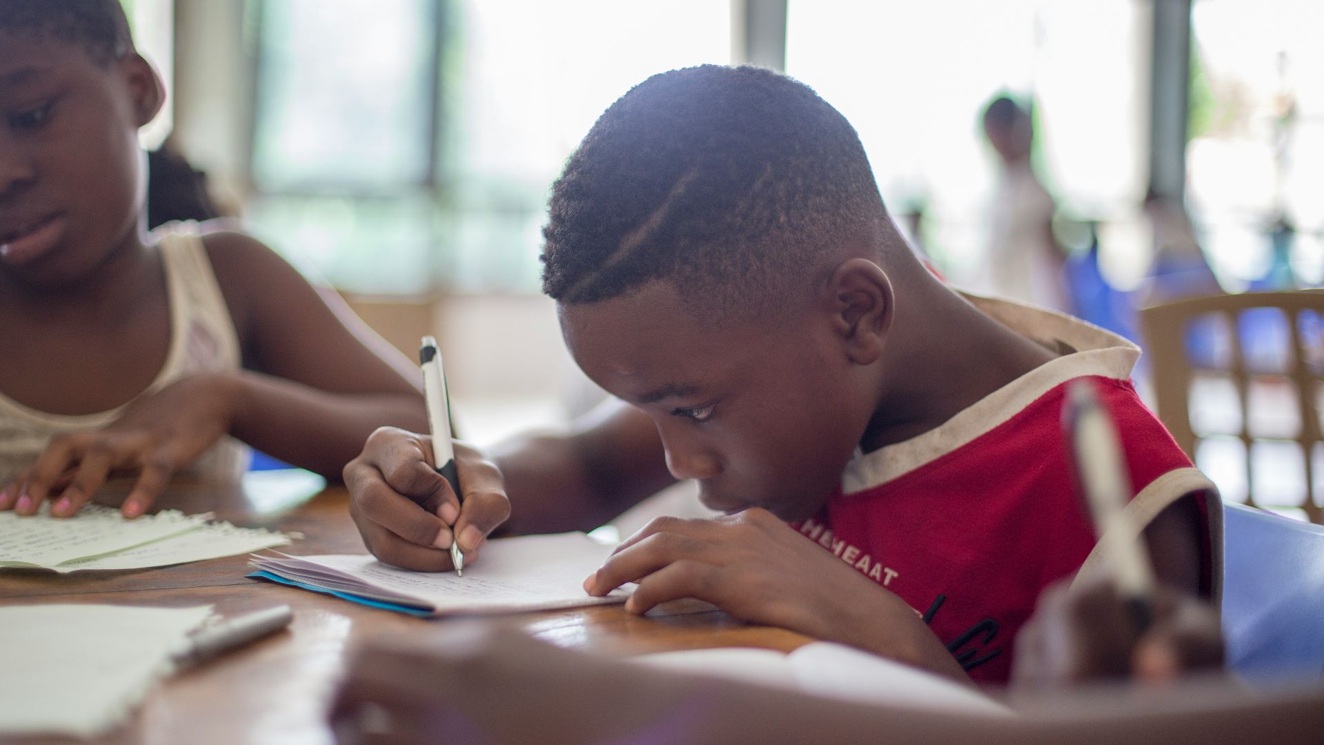 boy writing on printer paper near girl