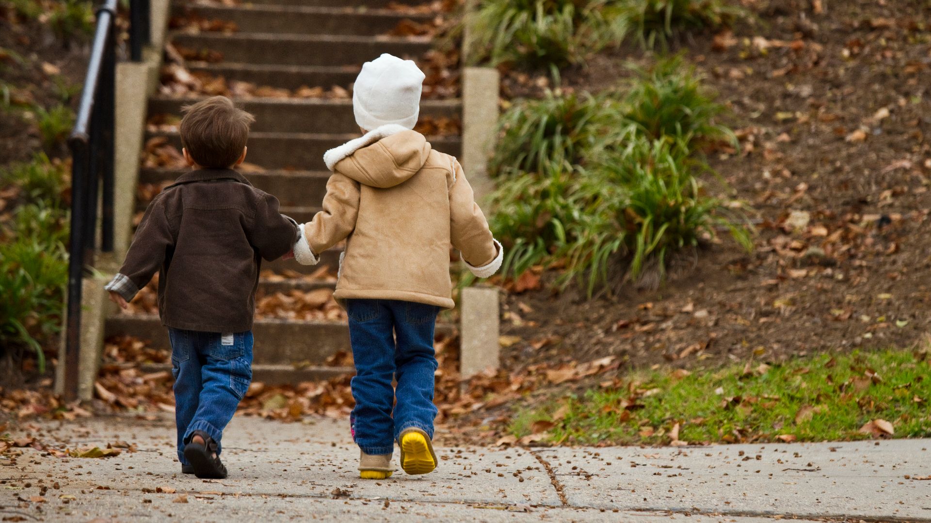 two toddlers walking towards stairs