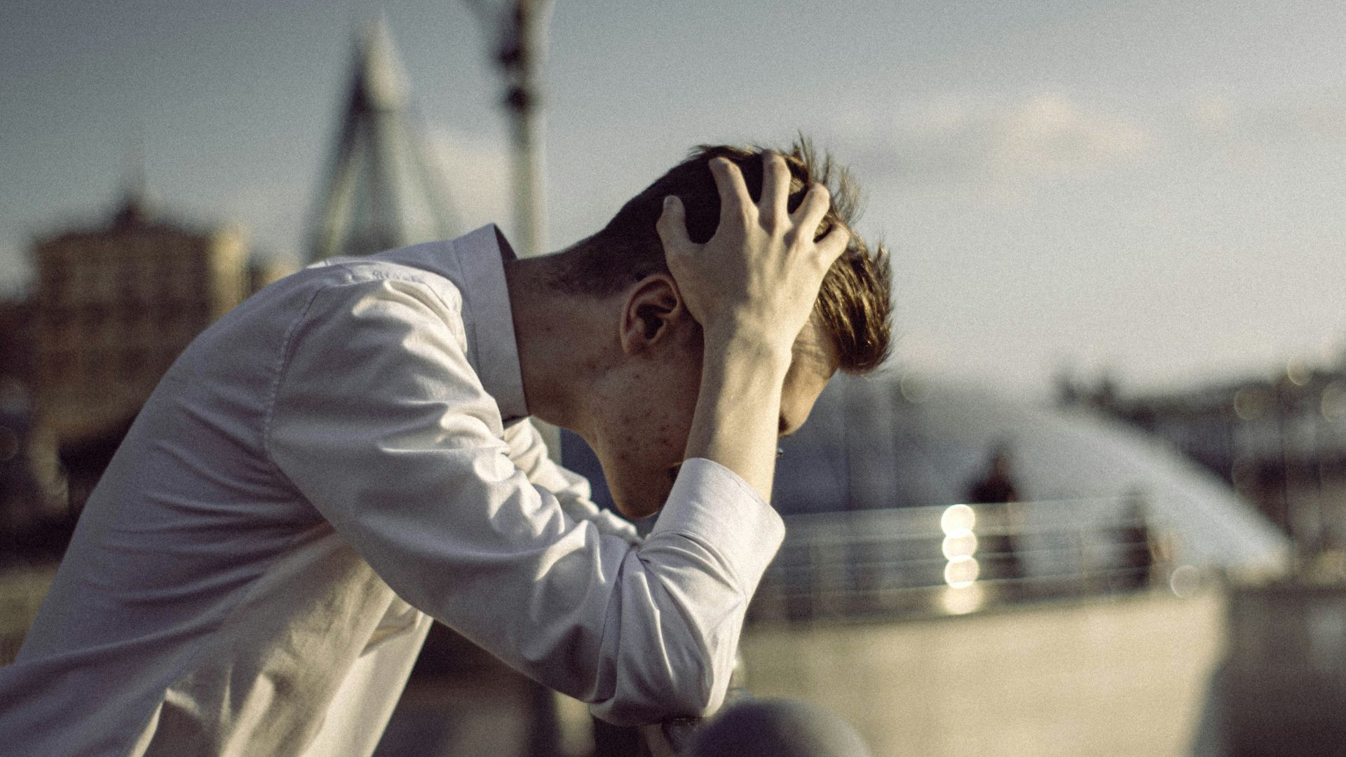 man in white dress shirt covering face with his hands