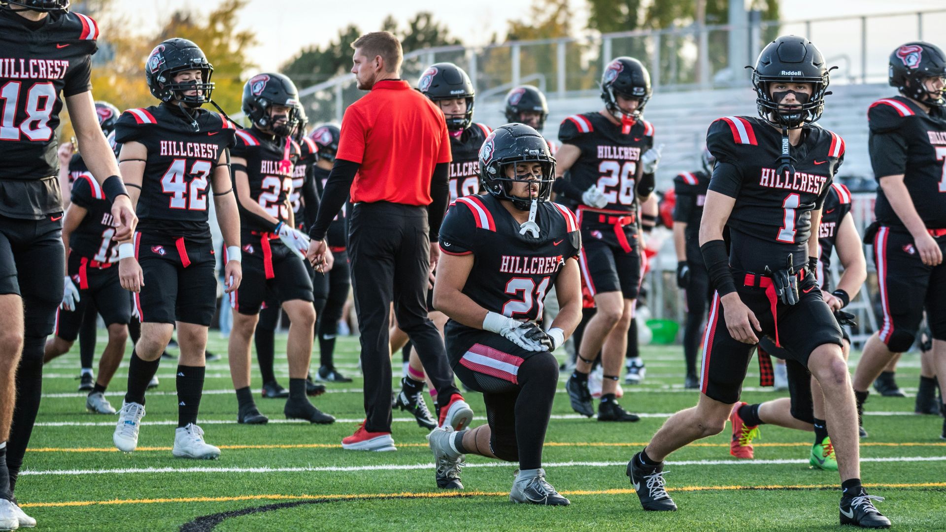 Football players in uniform stretching on field