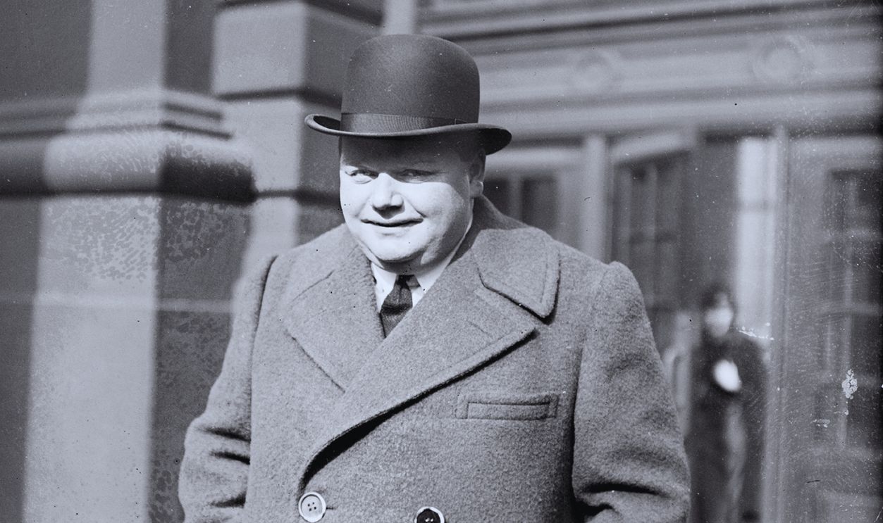 Gettyimages - 138146705, Fatty Arbuckle Roscoe (Fatty) Arbuckle, movie actor, standing with his hands in coat pockets on sidewalk, Chicago, Illinois, 1920. 