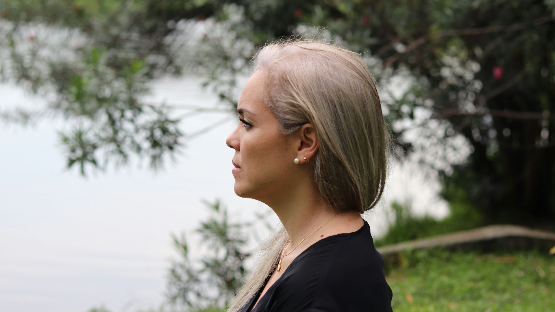 a woman with blonde hair standing in front of a body of water