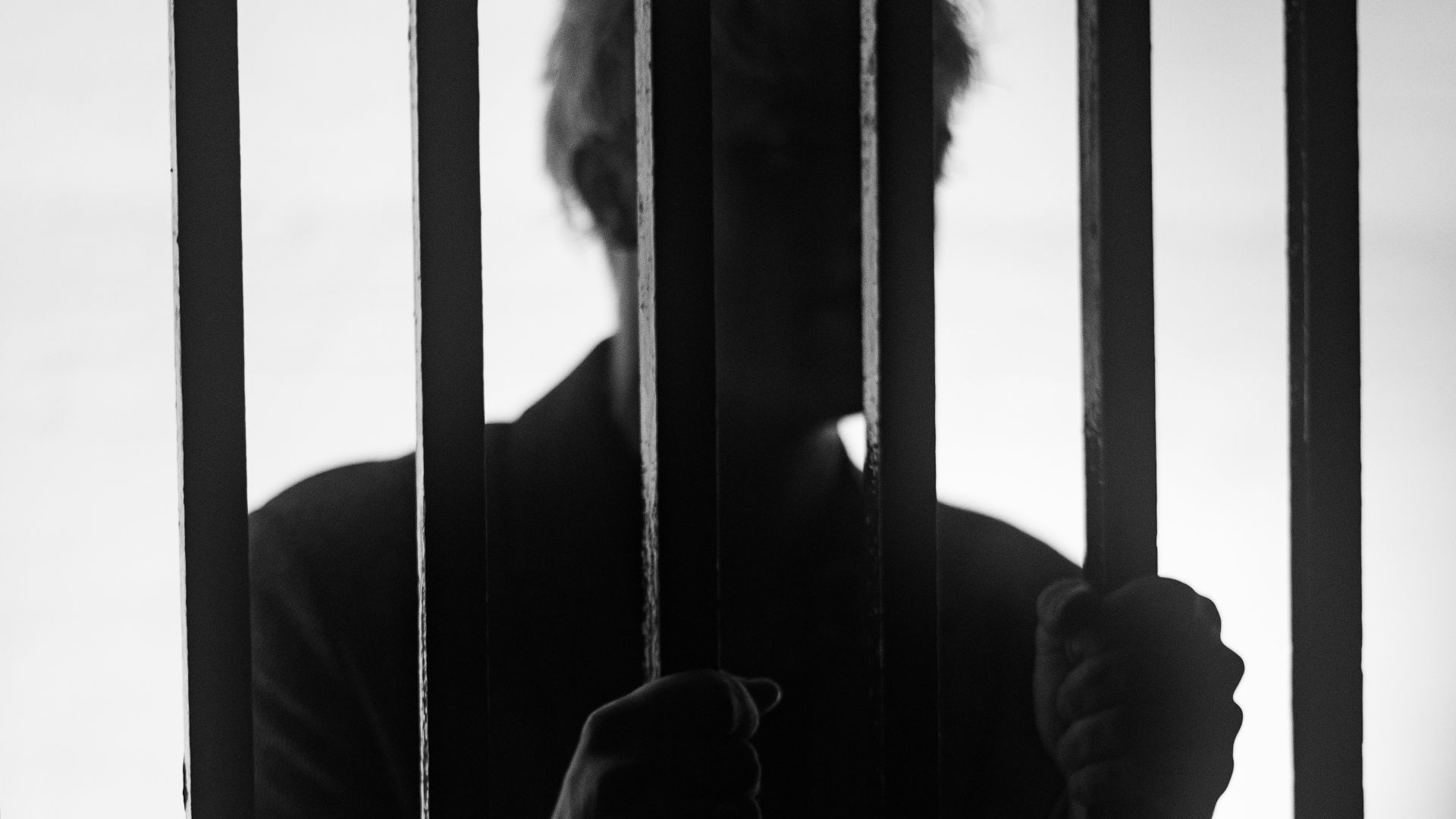 a man standing behind bars in a jail cell