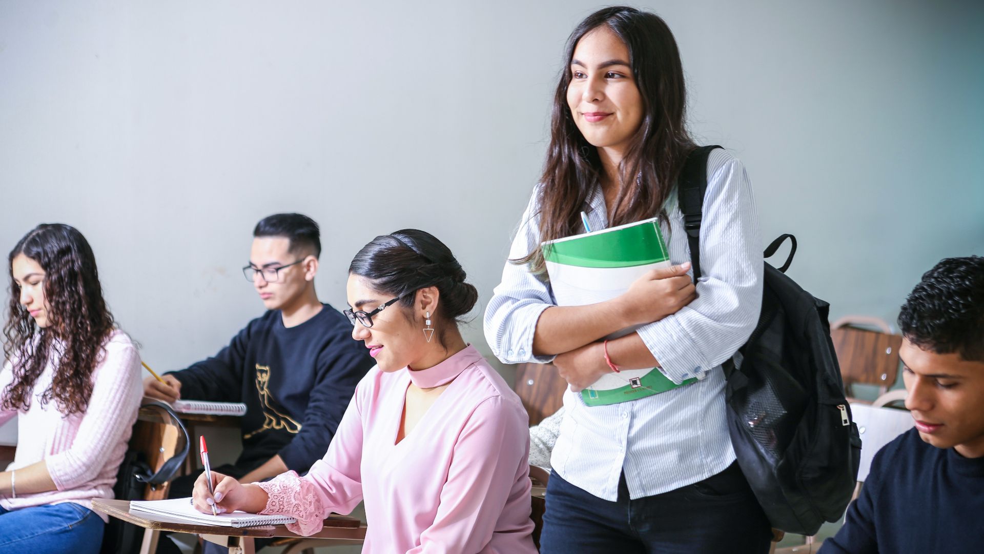 woman carrying white and green textbook