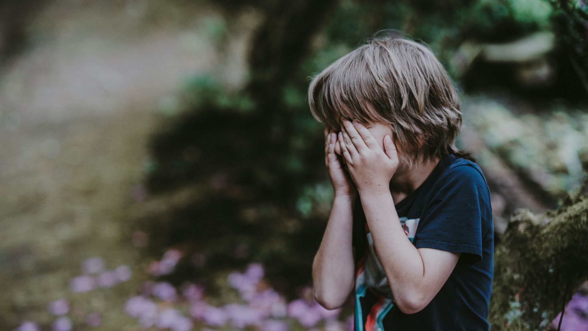 boy covering his face while standing
