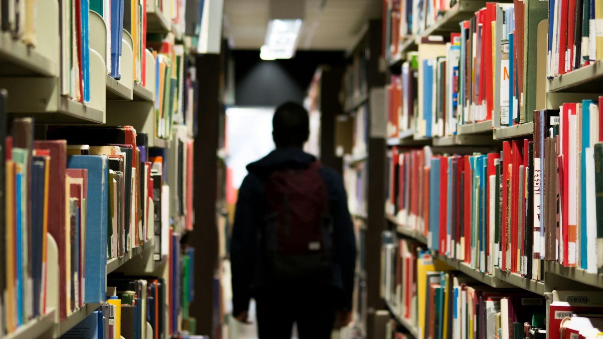 man with backpack beside a books