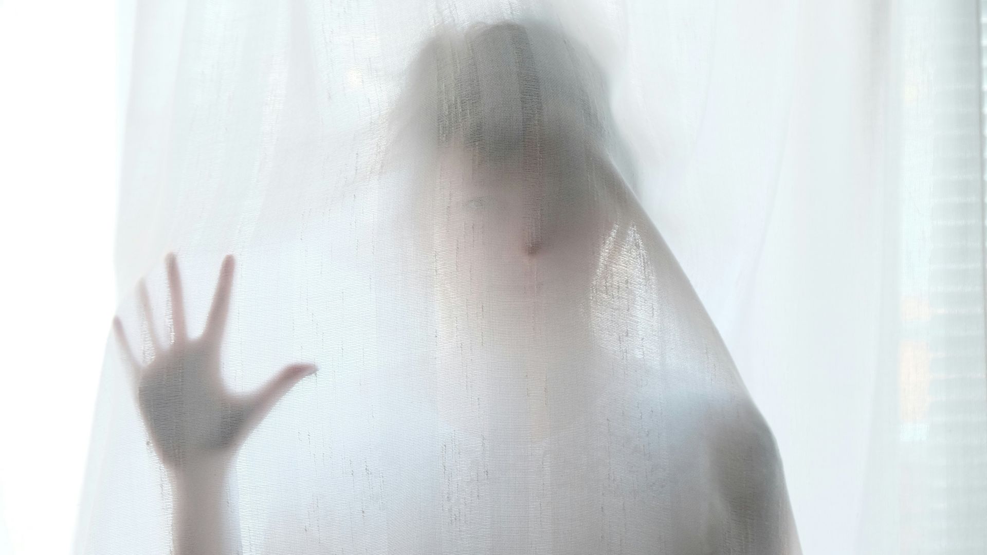 woman holding behind curtain