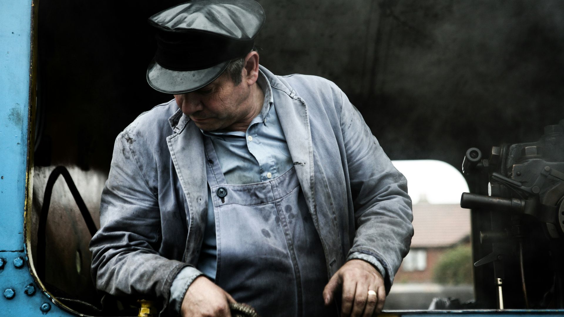 man in gray denim jacket and black hat holding black and brown short coated dog