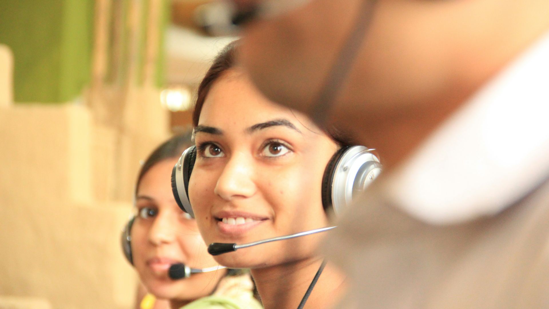woman in black headphones holding black and silver headphones